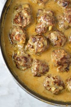 meatballs and gravy are in a pot on the stove top, ready to be cooked