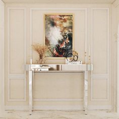 a white console table with a painting on the wall in an elegant living room setting