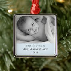 a baby's first christmas as an ornament hanging from a christmas tree