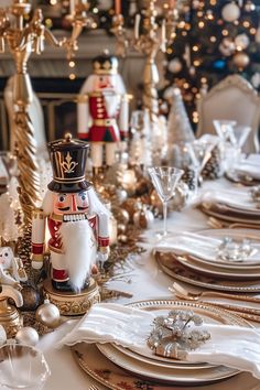 a table set for christmas dinner with gold and white plates, silverware, and nutcracker figurines