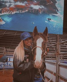 a woman standing next to a horse in front of a large screen