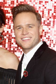 a man and woman standing next to each other in front of a sequin wall