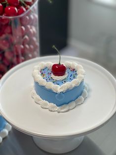 a heart - shaped cake with a cherry on top sits on a plate next to some strawberries