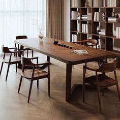 a dining room table with chairs and bookshelves