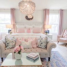 a white couch sitting in front of a bed next to a table with flowers on it