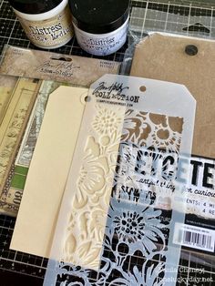 some crafting supplies are laying out on a cutting board with tags and paper attached to them