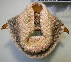 a crocheted scarf hanging from a hook on a wall next to a coat rack