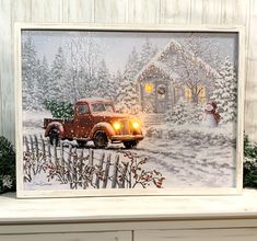 a christmas scene with an old red truck in front of a snow covered house and tree