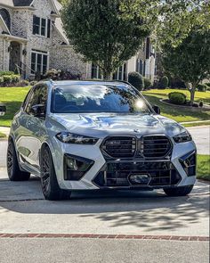 a silver bmw suv parked in front of a house