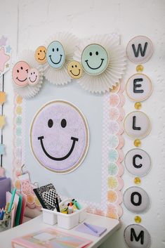 a white desk topped with a mirror next to a wall covered in paper flowers and smiley faces