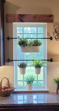 a kitchen window with three planters on the ledge