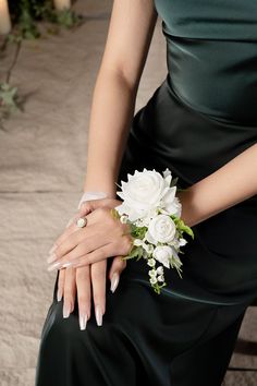 a woman in a green dress holding a bouquet of white flowers on her lapel