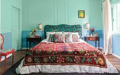 a bedroom with blue walls and red bedspread, two chairs, and a bed in the middle