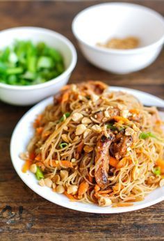 a white plate topped with noodles and veggies next to two bowls of sauce