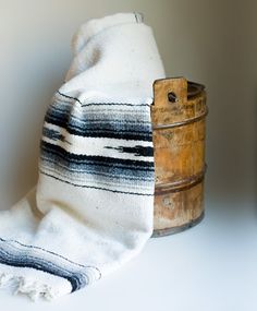 an old wooden bucket with a white and black blanket on it next to a towel