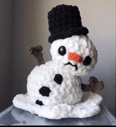 a crocheted snowman sitting on top of a plastic container