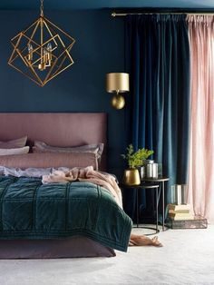 a bedroom with blue walls, gold accents and green bedding in the center is a chandelier