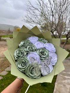 a person holding a bouquet of paper flowers in their hand with a butterfly on it