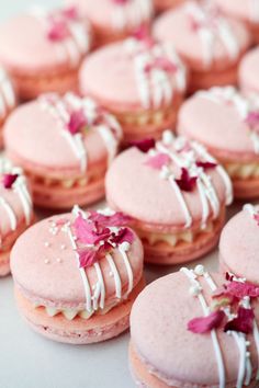 pink macaroons with white icing and flowers on them are arranged in a circle