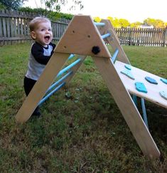 a toddler playing in the yard with a wooden play set that is made out of plywood