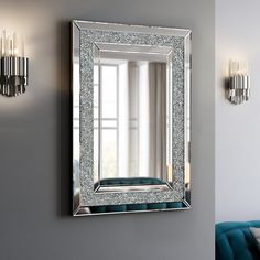 a mirror mounted to the side of a wall next to a blue couch and chandelier