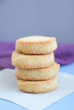 three sugar cookies stacked on top of each other next to a blue napkin and purple cloth