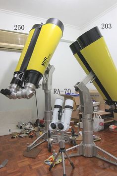 two yellow and black telescopes on top of a wooden floor