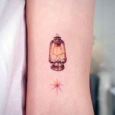 a small tattoo on the arm of a girl with a lantern and star in it