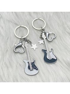 two key chains with guitars on them sitting on top of a white fur covered surface