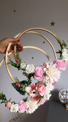 a person is holding two hoop wreaths with flowers on them