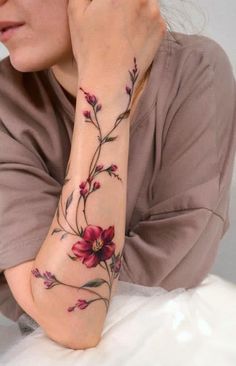 a woman with a flower tattoo on her arm and hand is looking at the camera