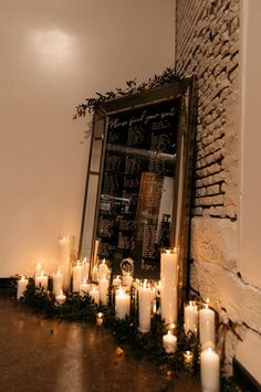 candles are lined up in front of a chalkboard with menus on it and greenery