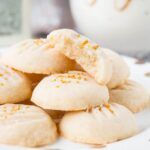 a pile of cookies sitting on top of a white plate next to a glass vase