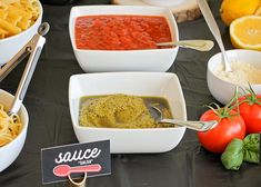 various bowls of pasta and sauce on a table with tomatoes, lemons, basil, garlic, parmesan cheese