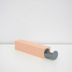 a pink and gray object sitting on top of a white table next to a wall