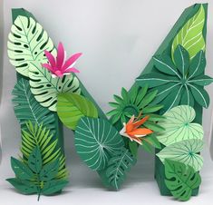 the letter m is made out of paper with tropical leaves and flowers on it's sides