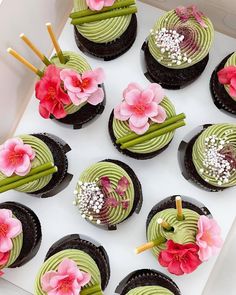 cupcakes decorated with flowers and sticks in a box