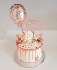 a birthday cake decorated with pink and white icing, topped with a large balloon