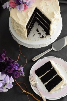 there is a piece of cake on the plate next to the knife and fork, with purple flowers in the background