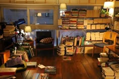 a room filled with lots of books next to a desk and chair in front of a window