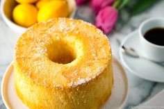 a cake sitting on top of a white plate next to some flowers and lemons