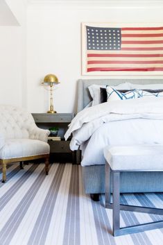 a bedroom with an american flag on the wall and a chair in front of it