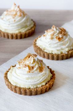 three small desserts with white frosting and toasted coconut on top