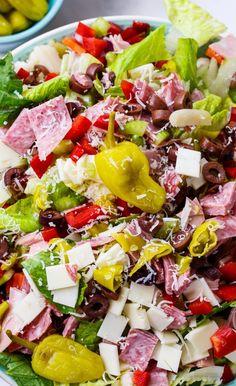 a salad with meat, cheese and olives in a bowl