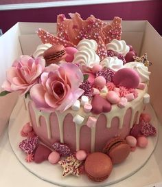 a pink cake with white frosting and flowers on top is in a cardboard box