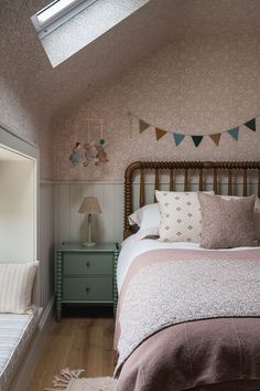 a bed sitting in a bedroom next to a window with a skylight above it