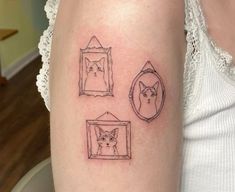 a woman's arm with three small tattoos on it, including a cat and a mirror