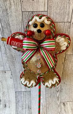 a christmas ornament shaped like a gingerbread man holding a candy cane with the word cookies on it