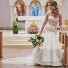 a beautiful woman in a wedding dress standing at the alter with her hands on her hips