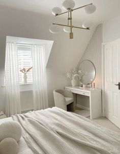 a bedroom with a white bed, dresser and mirror in it's corner next to a window